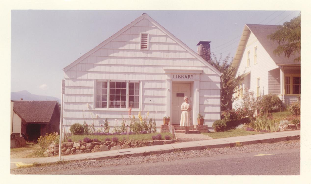 Photo of a library worker standing in front of the Stevenson Community Library building, pre-1967.